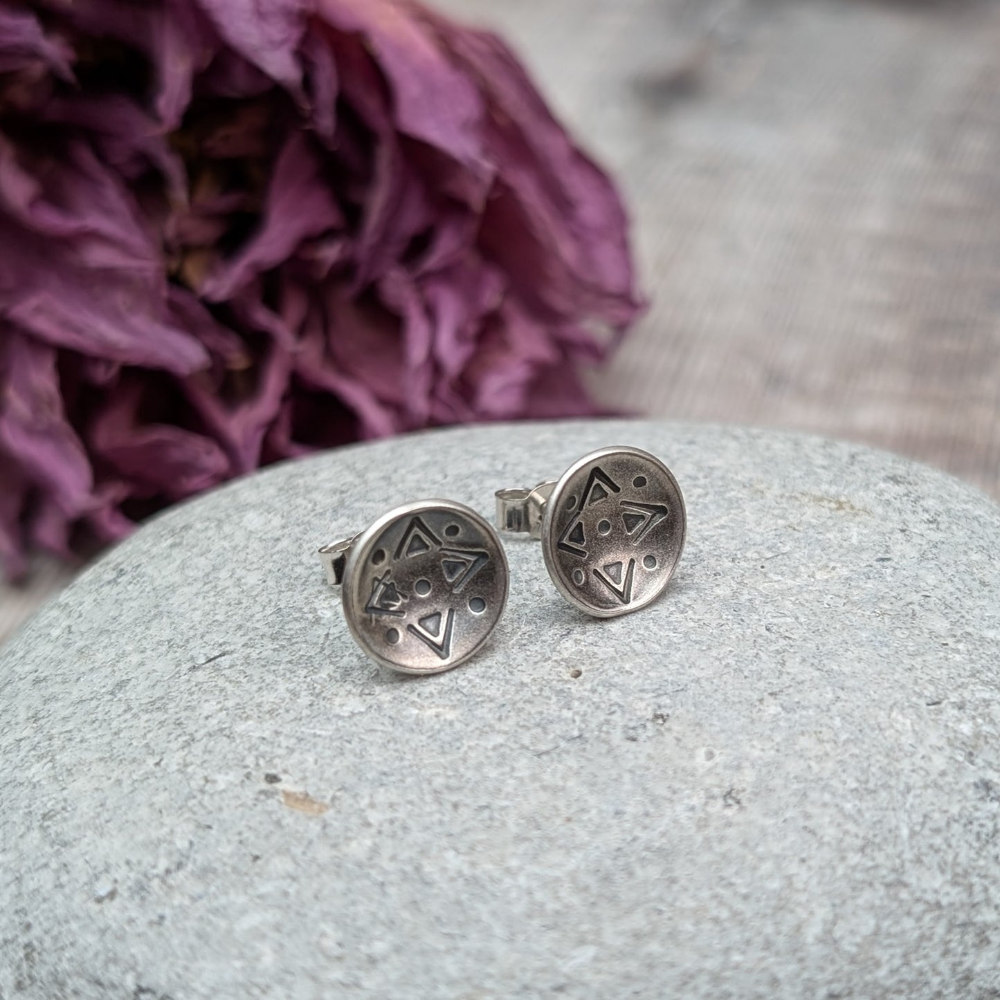 Oxidised Sterling Silver dome shaped disc attached to silver earring bar. Each earring has geometric triangular and dot patterns on the inside of the curved dome.