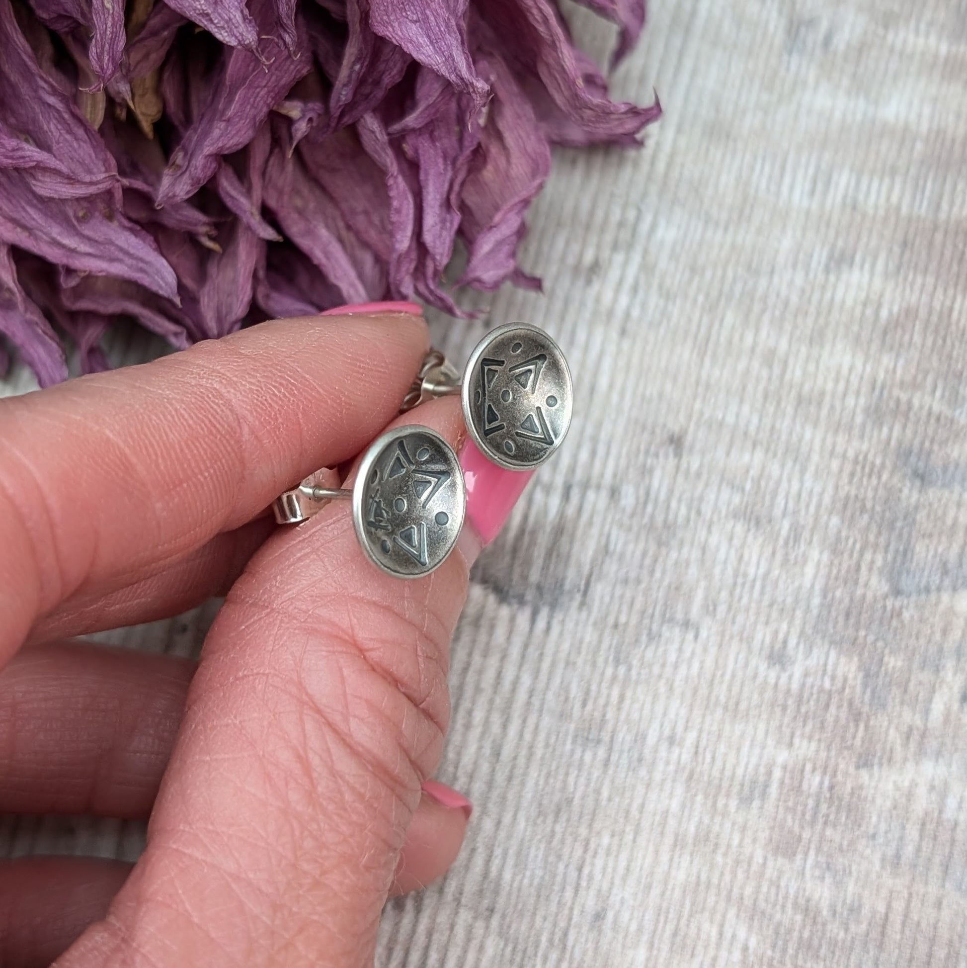 Oxidised Sterling Silver dome shaped disc attached to silver earring bar. Each earring has geometric triangular and dot patterns on the inside of the curved dome.