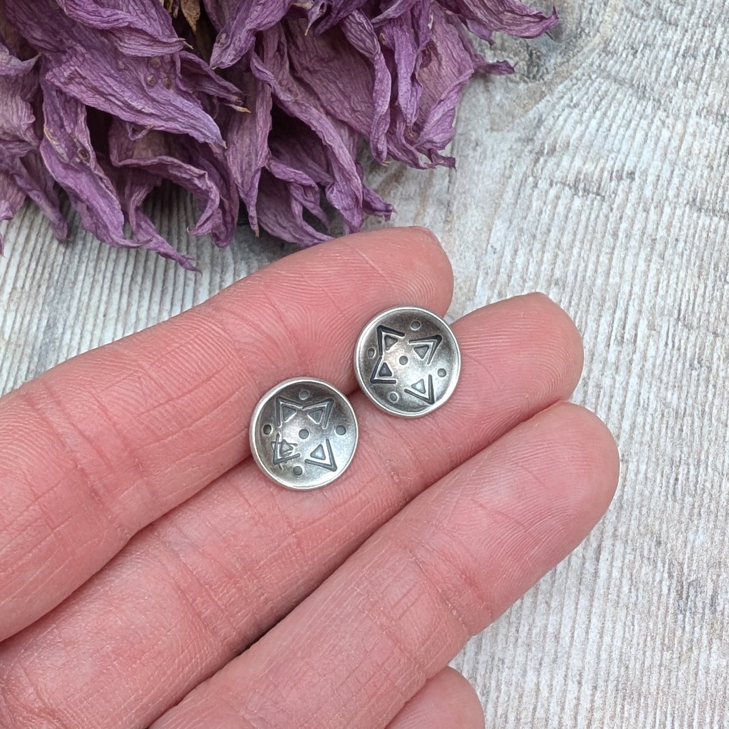 Oxidised Sterling Silver dome shaped disc attached to silver earring bar. Each earring has geometric triangular and dot patterns on the inside of the curved dome.