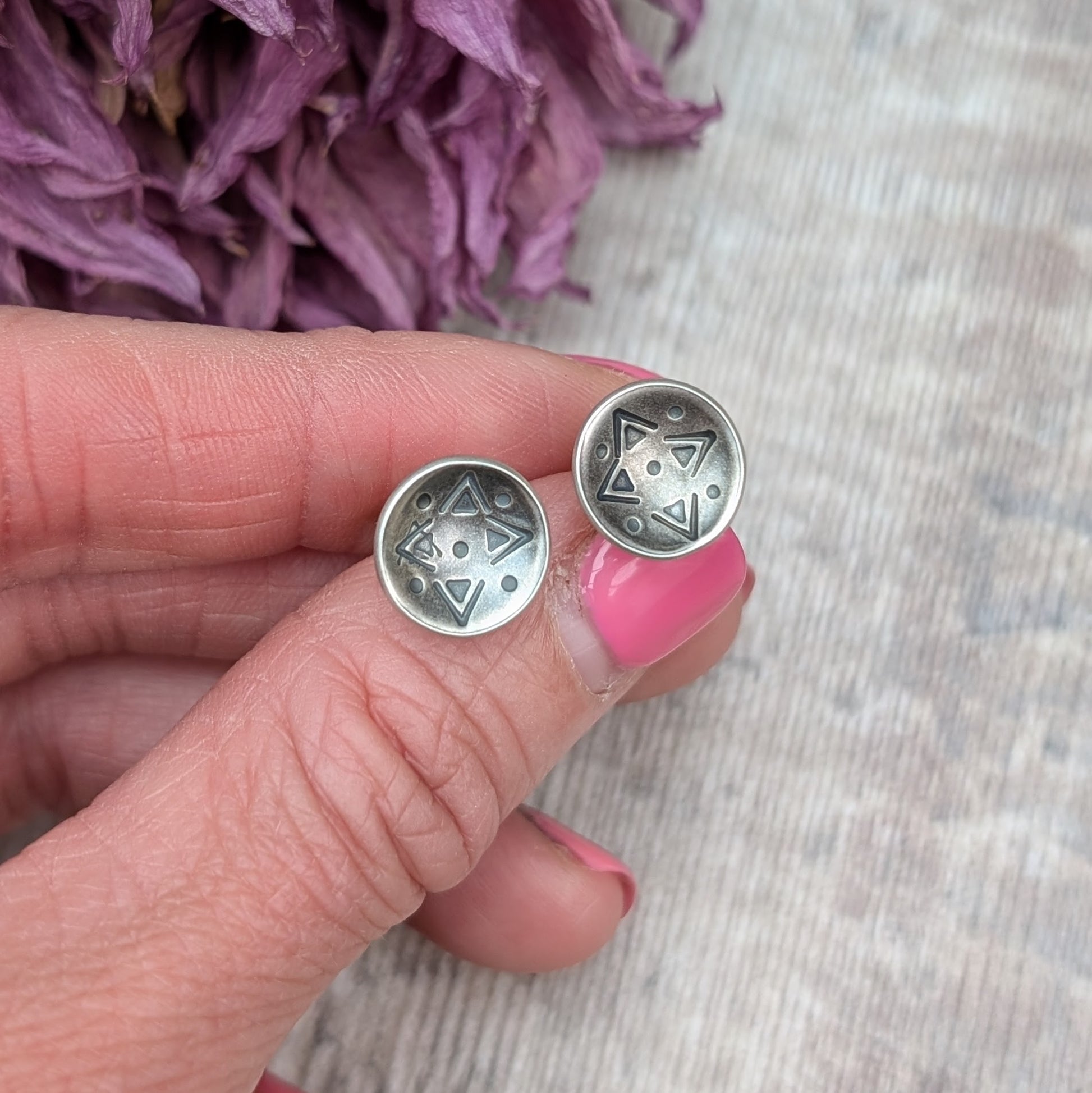 Oxidised Sterling Silver dome shaped disc attached to silver earring bar. Each earring has geometric triangular and dot patterns on the inside of the curved dome.