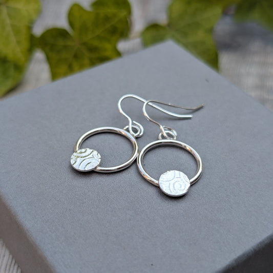 Circle earring with textured disc handmade from recycled Sterling Silver displayed on a grey jewellery box.
