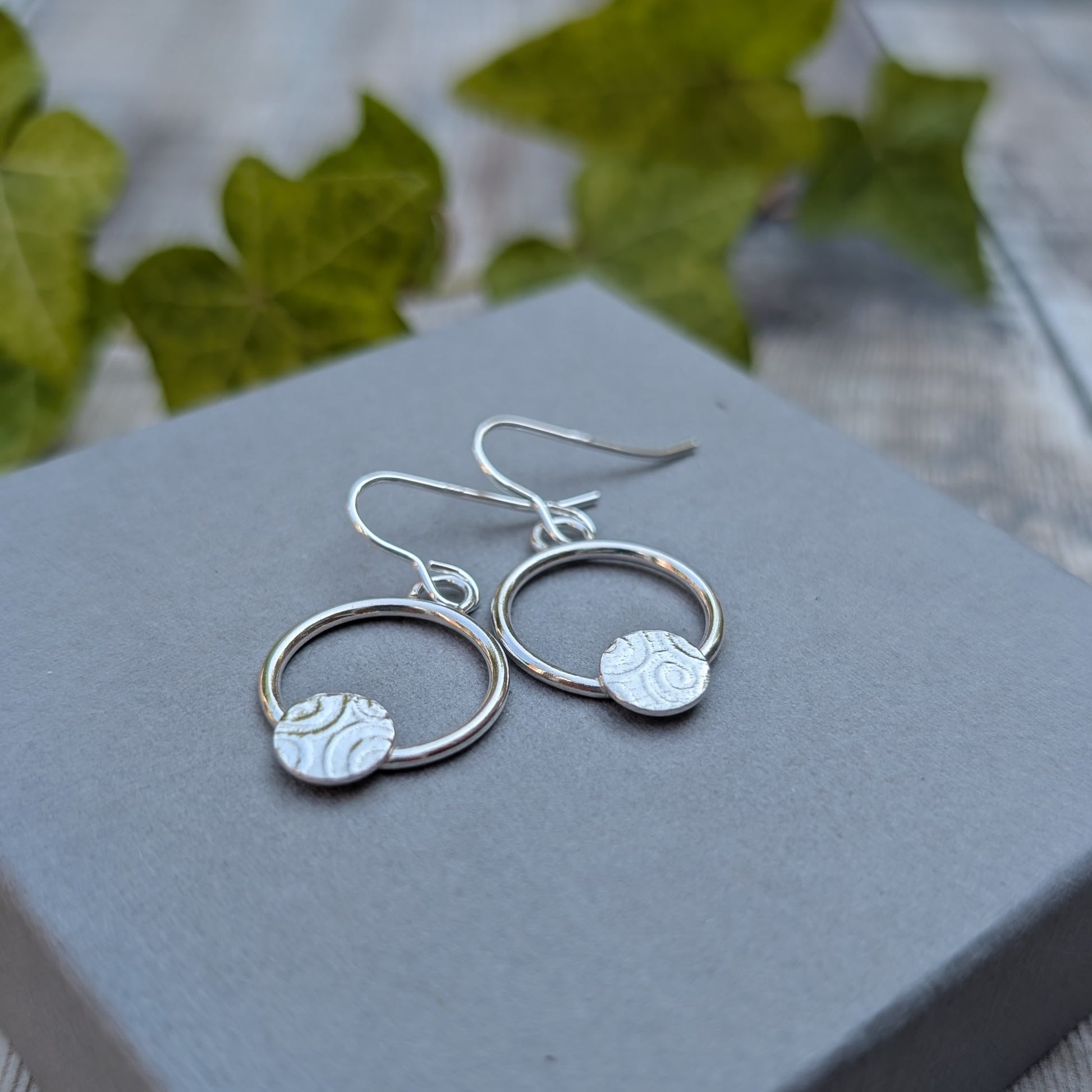 Close up of circle earring with textured disc handmade from recycled Sterling Silver showing the textured silver discs.