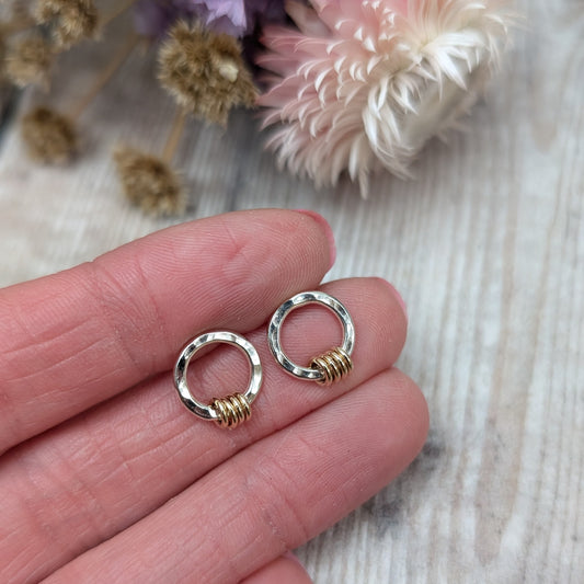 Each earring is an open circle with hammered texture, mounted on stud bar. Threaded through the circle are four small gold circles that move independently.