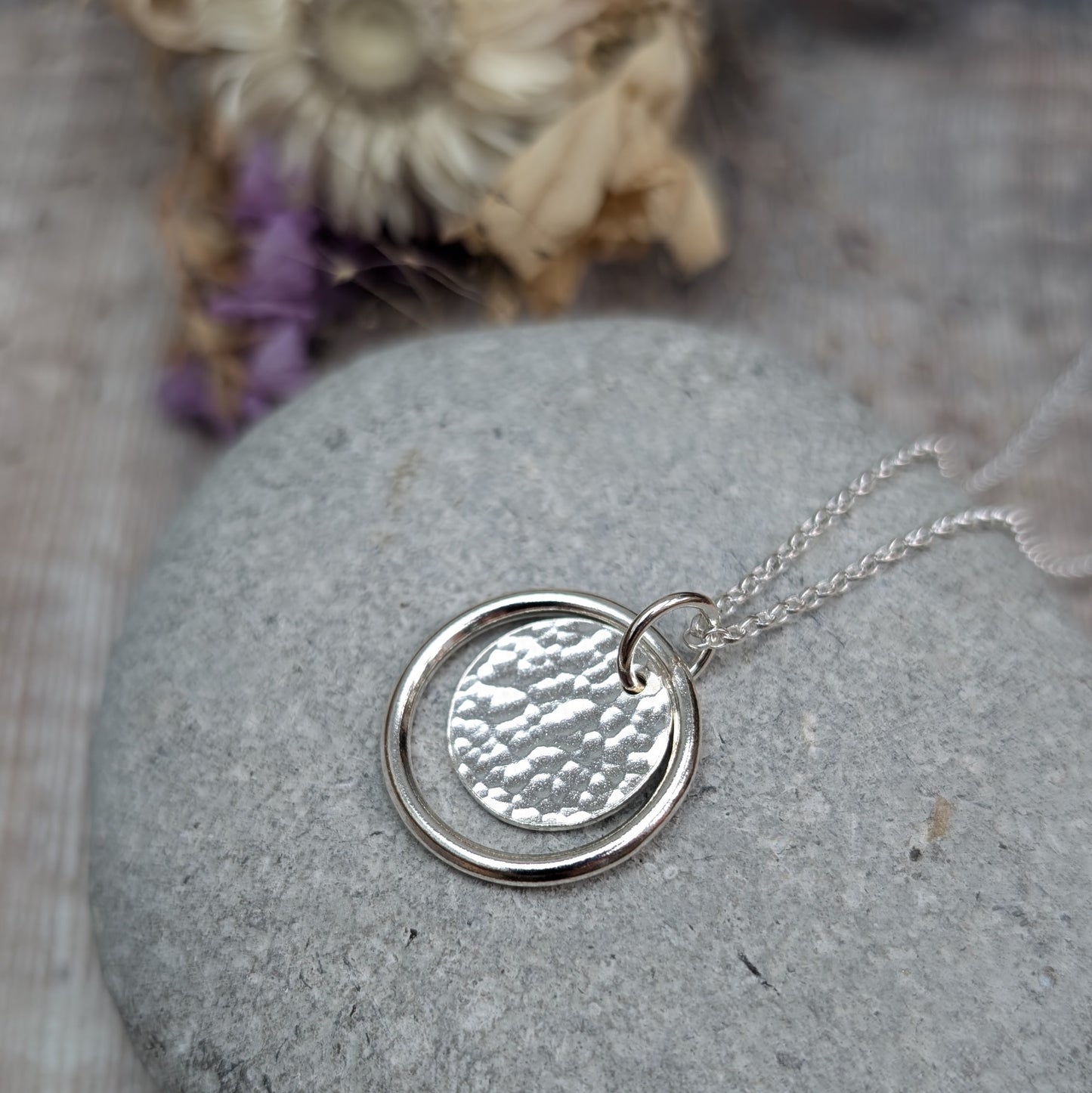 Sterling Silver smooth circle pendant with hammered silver disc sitting inside, suspended from a silver circle link attached to silver chain. 