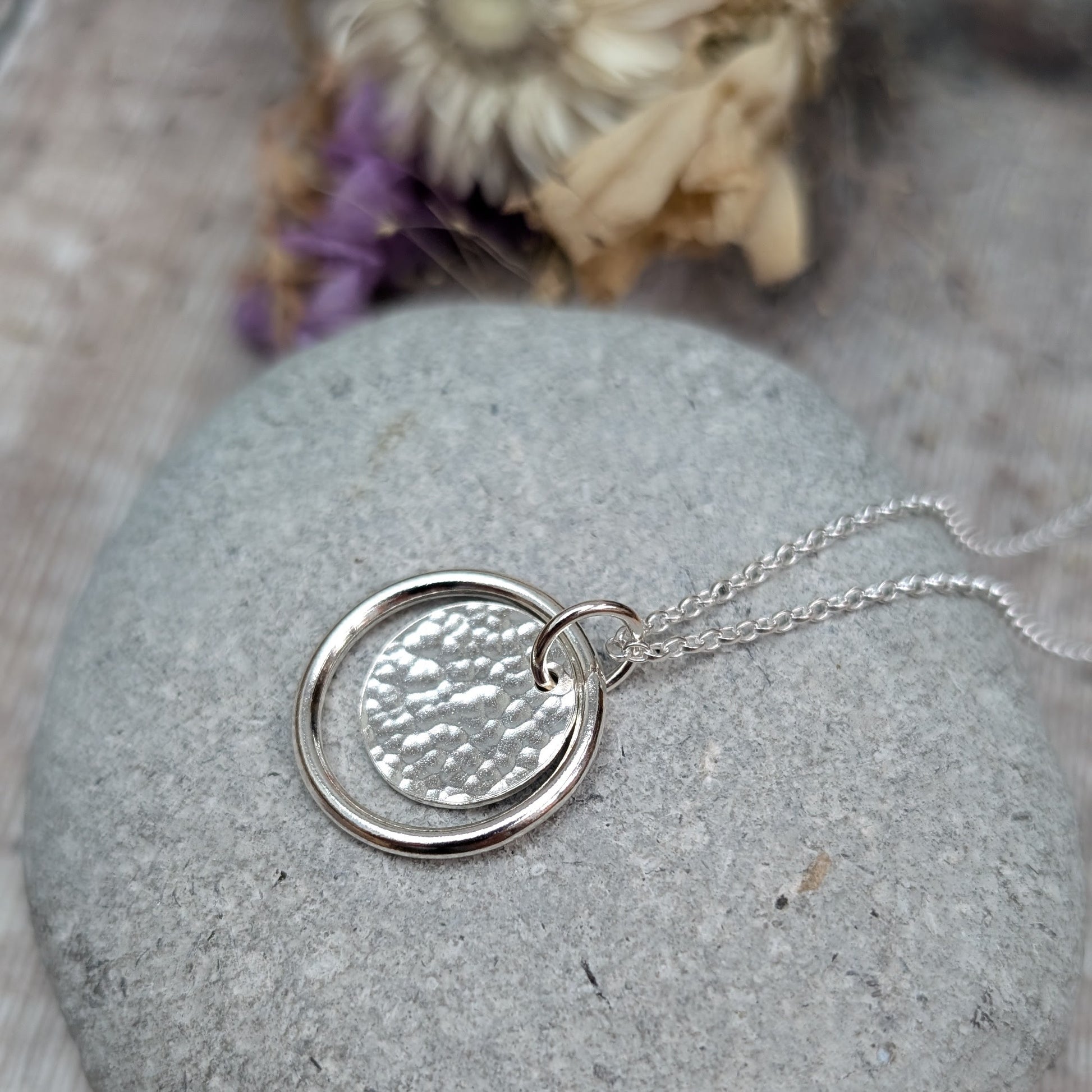 Sterling Silver smooth circle pendant with hammered silver disc sitting inside, suspended from a silver circle link attached to silver chain. 