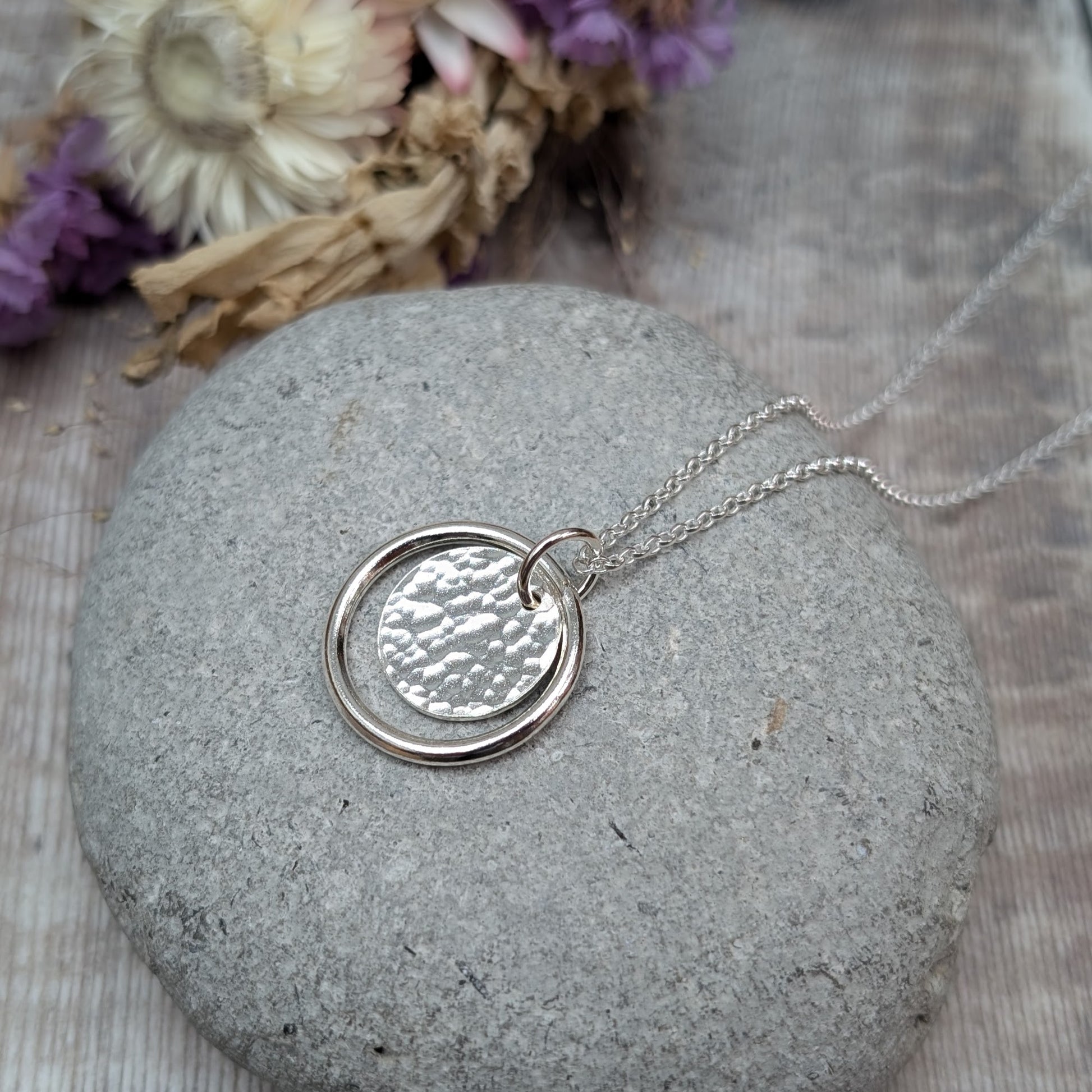 Sterling Silver smooth circle pendant with hammered silver disc sitting inside, suspended from a silver circle link attached to silver chain. 