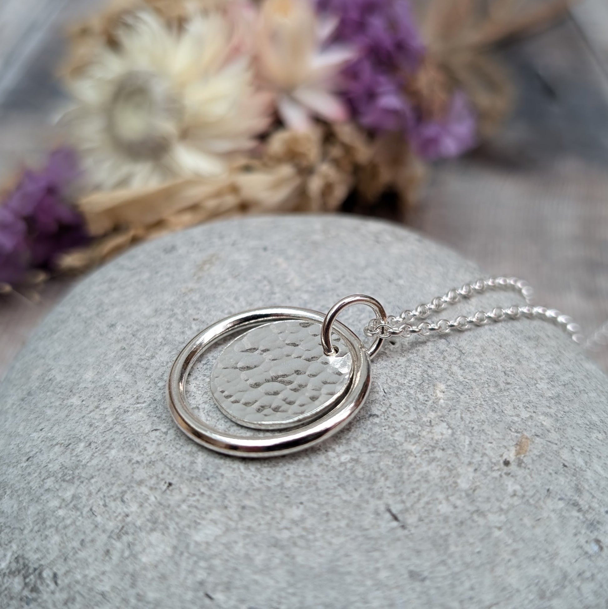 Sterling Silver smooth circle pendant with hammered silver disc sitting inside, suspended from a silver circle link attached to silver chain. 