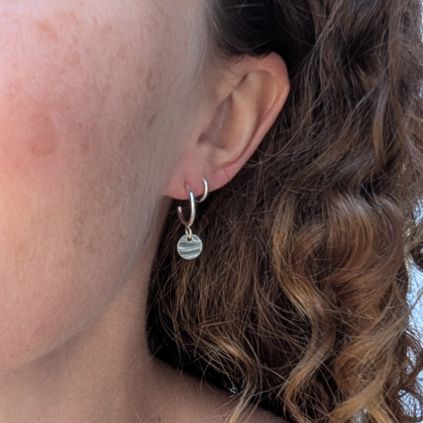 Silver disc drop hoop earrings handmade from recycled Sterling Silver, worn in the ear to show their size and everyday fit.