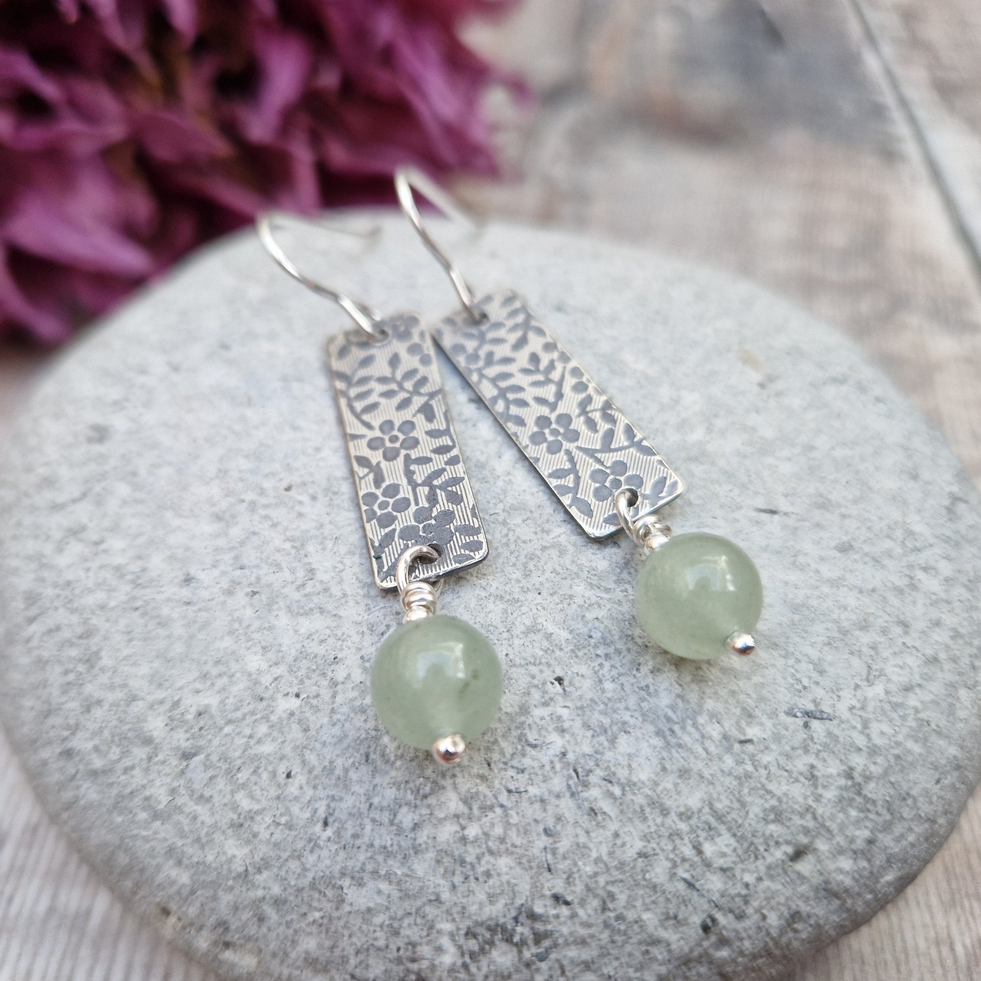 Each earring is a Sterling Silver rectangle stamped with a floral design suspended from earring wire. Suspended from the bottom of the rectangle is an Aventurine sphere gemstone, pale green/off white in colour.