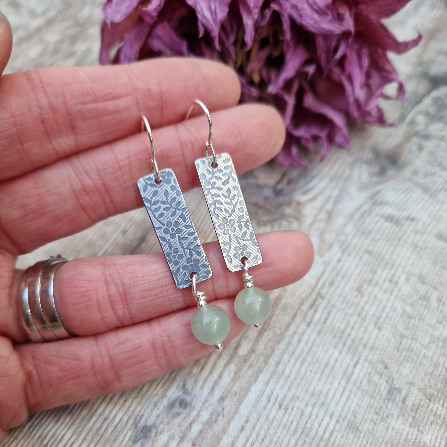 Each earring is a Sterling Silver rectangle stamped with a floral design suspended from earring wire. Suspended from the bottom of the rectangle is an Aventurine sphere gemstone, pale green/off white in colour.