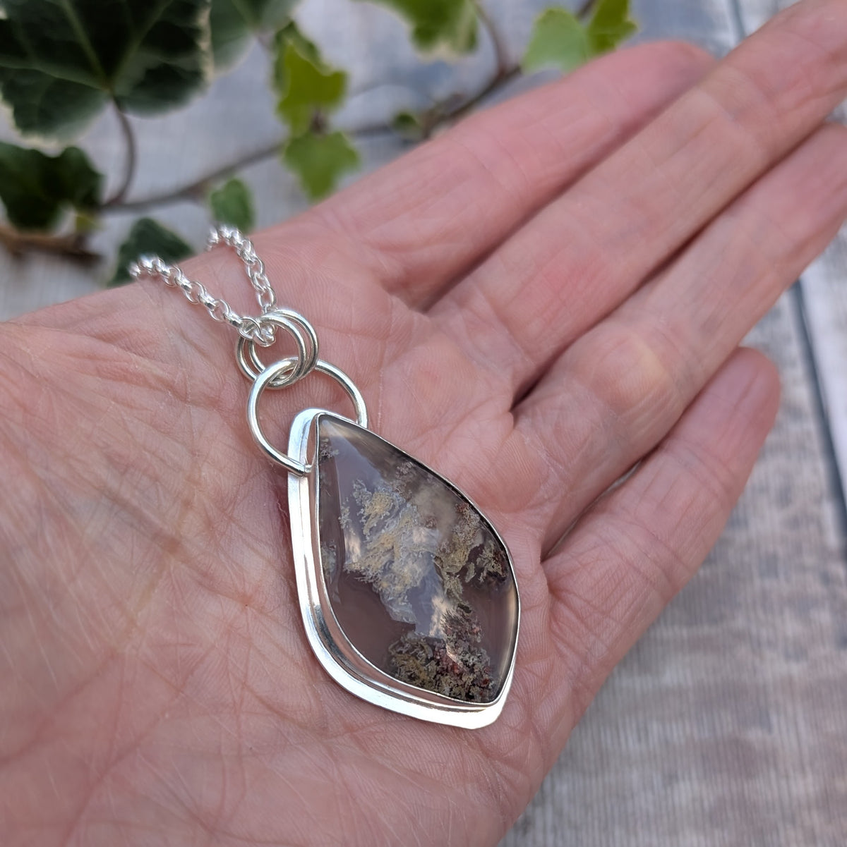 Close up of Garden Moss Agate Statement Gemstone Necklace showing the polished sterling silver setting, circular silver links and natural moss-like patterns within the gemstone.