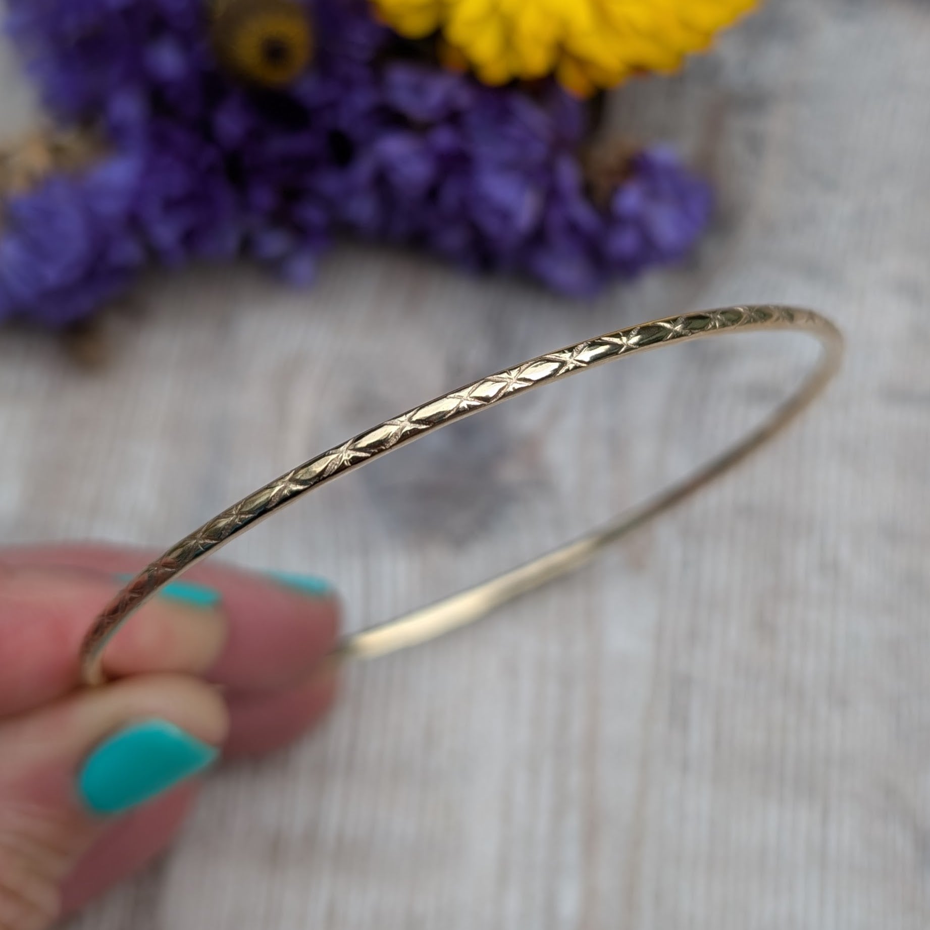 Slim gold bangle decorated with indented starlight pattern.