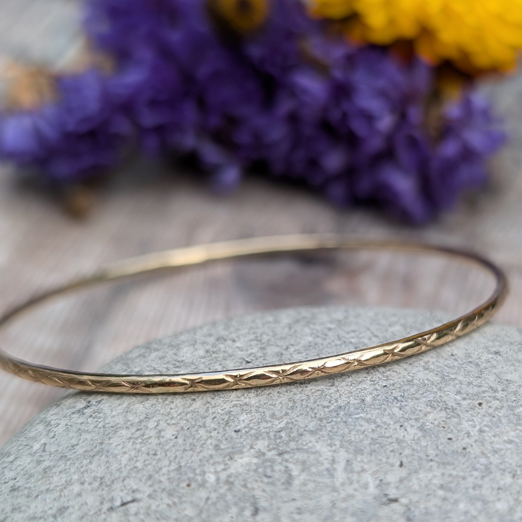 Slim gold bangle decorated with indented starlight pattern.