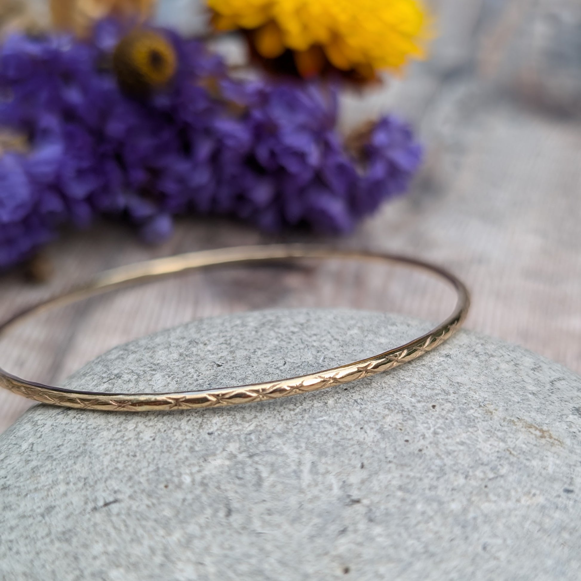 Slim gold bangle decorated with indented starlight pattern.