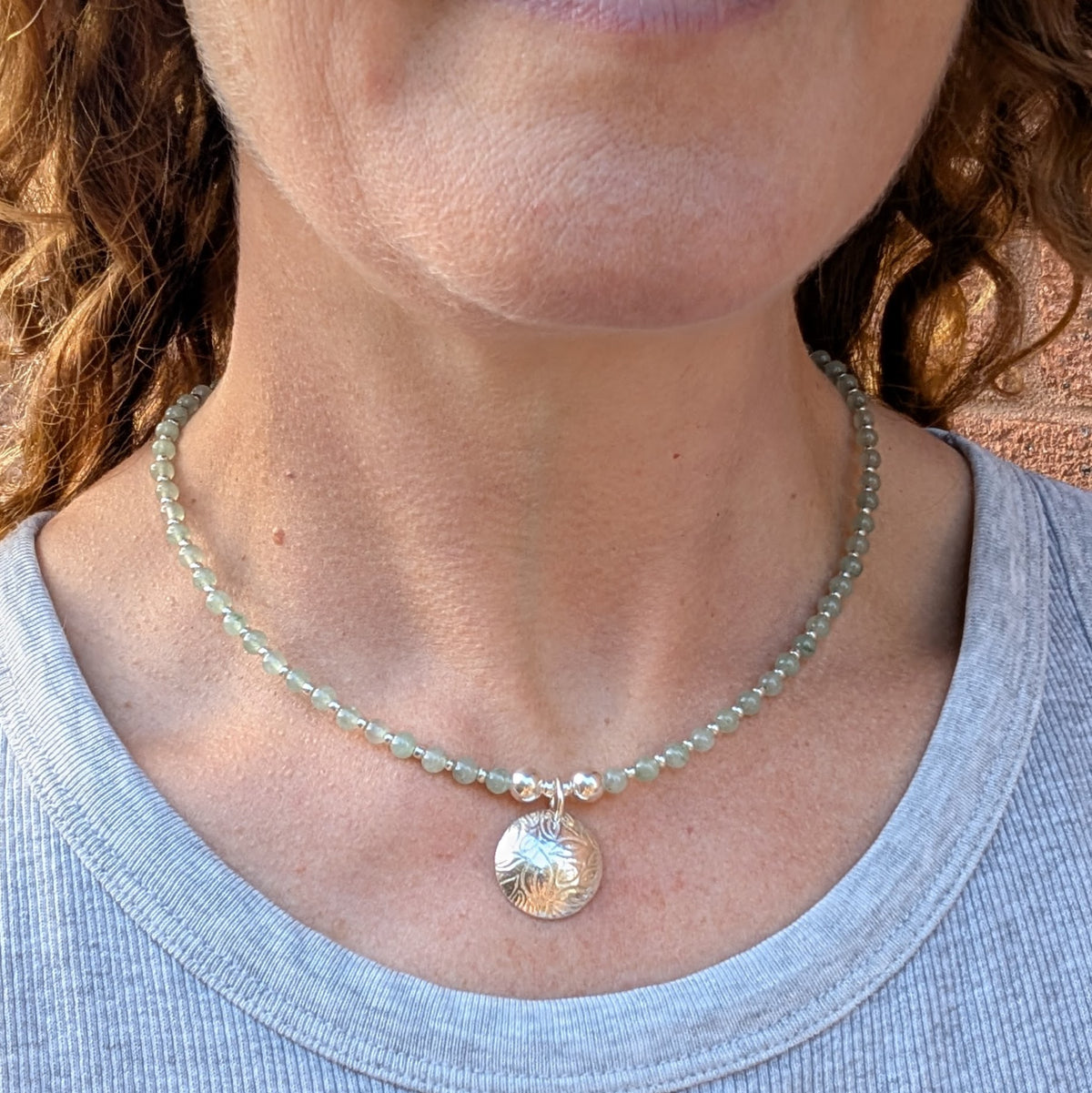 Green Aventurine and Silver Leaf Disc Necklace being worn around the neck, showing how the green gemstone beads and handmade silver leaf charm sit when worn.