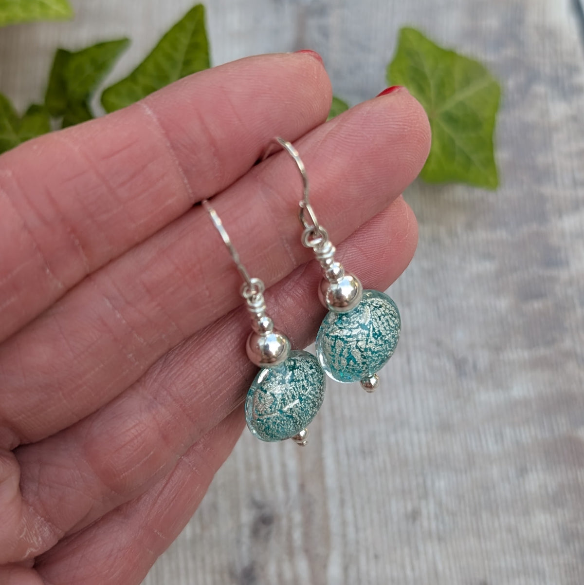 Close up of green venetian glass silver earrings with handmade round green glass beads and recycled sterling silver ear wires.