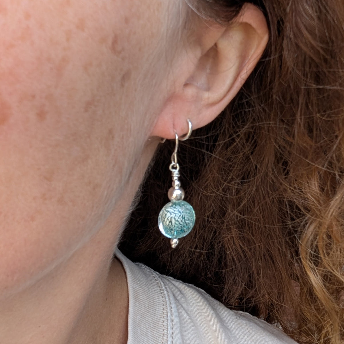 green venetian glass silver earrings being worn, showing the size and drop of the round green Venetian glass bead.