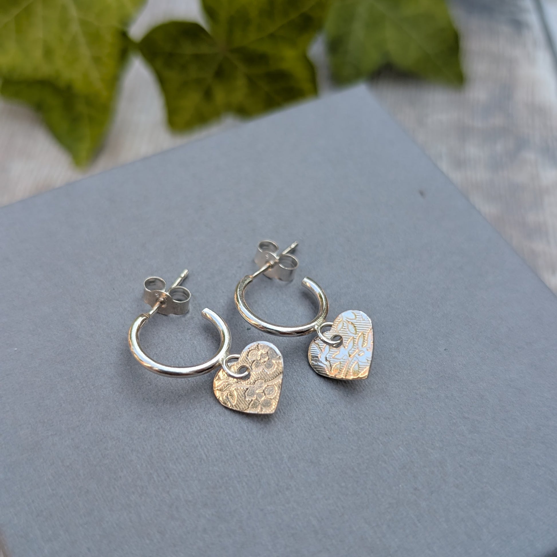 Silver heart drop hoop earrings handmade from recycled Sterling Silver photographed on a grey jewellery box from the back.
