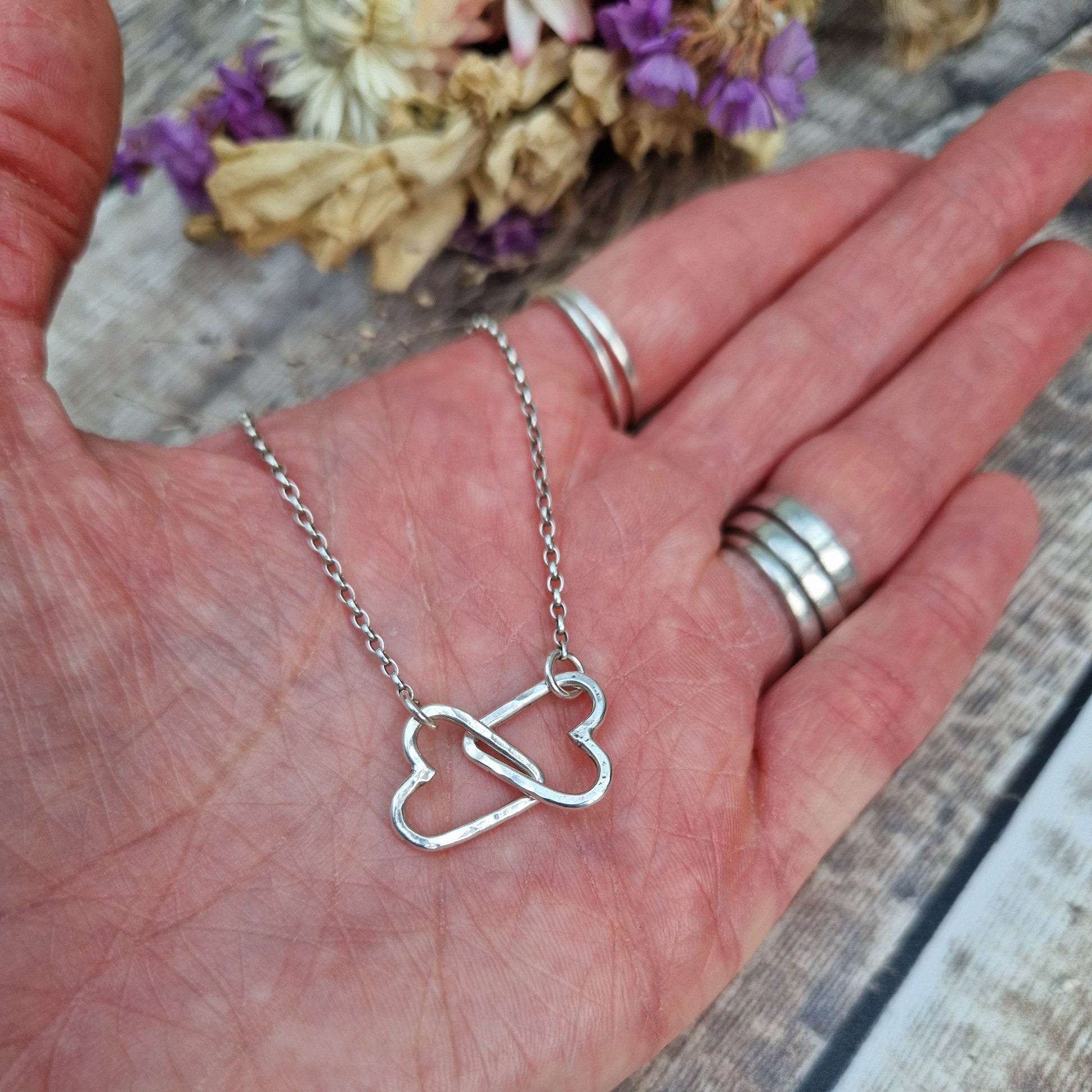 Pendant is two Sterling Silver open hearts with hammered texture, linked to each other. Suspended from silver chain via a small circle link attached to each heart.