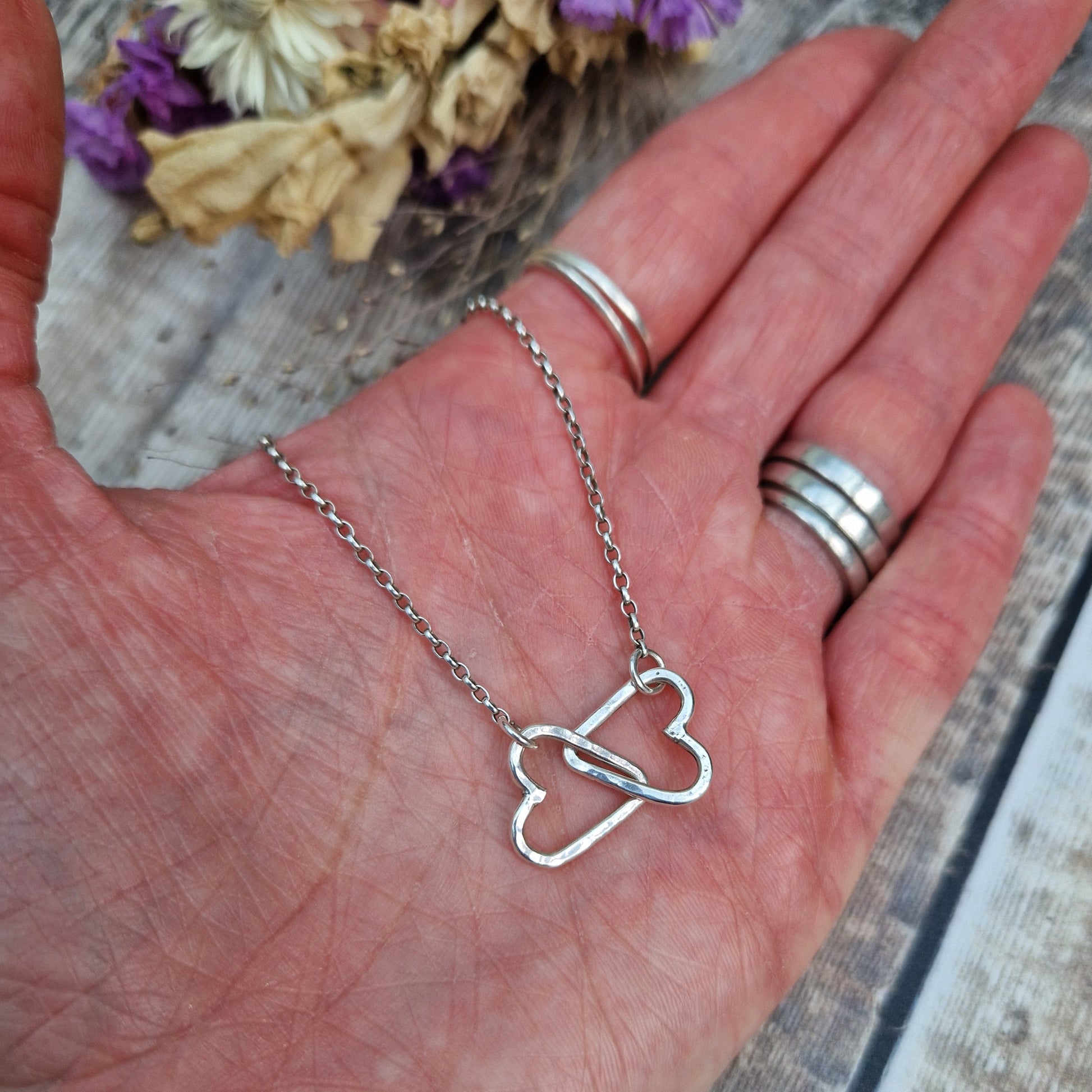 Pendant is two Sterling Silver open hearts with hammered texture, linked to each other. Suspended from silver chain via a small circle link attached to each heart.