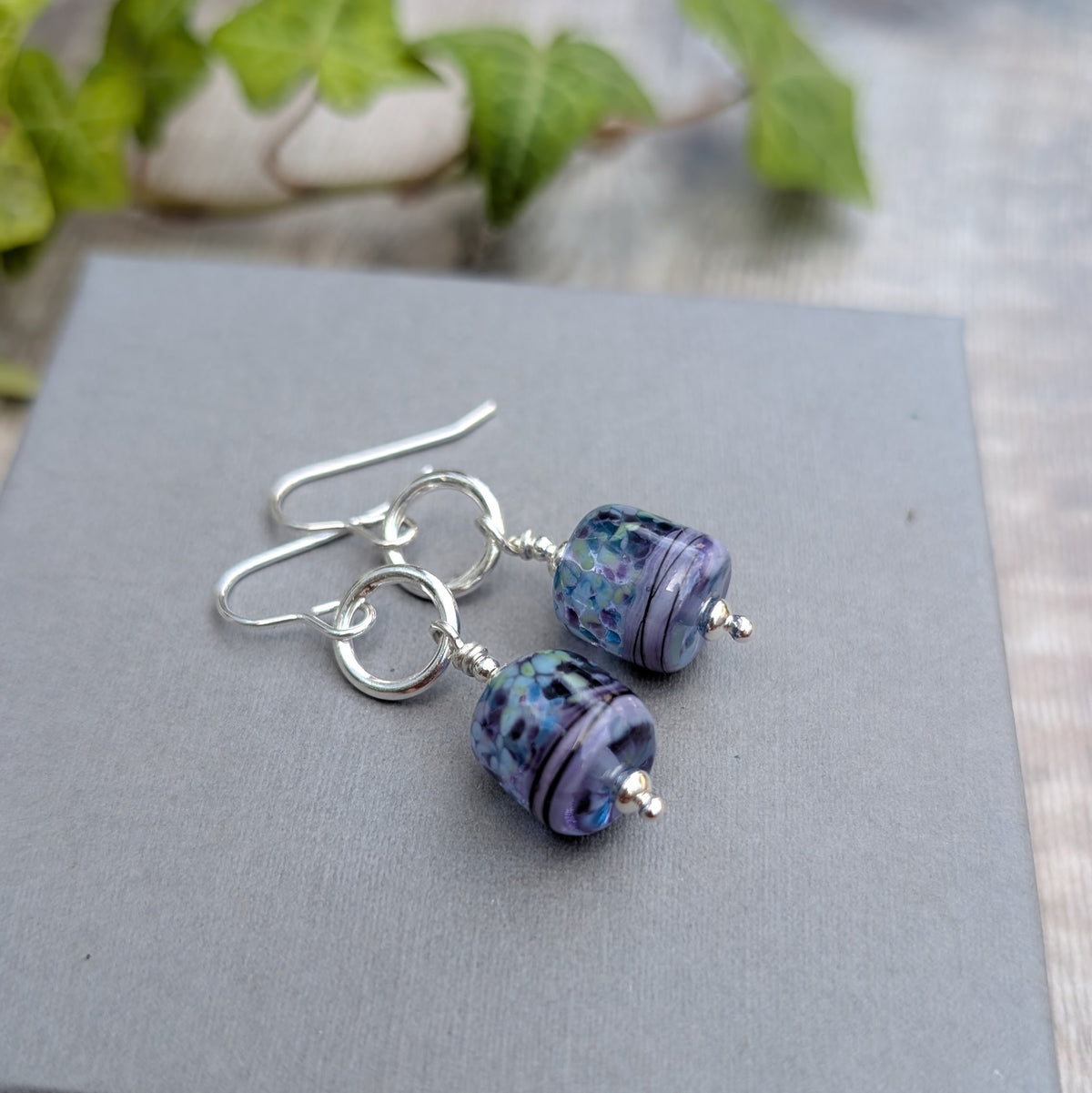 Close up of Lilac Watercolour Lampwork Glass and Silver Circle Earrings showing the handmade glass beads and recycled Sterling Silver circles and ear wires.