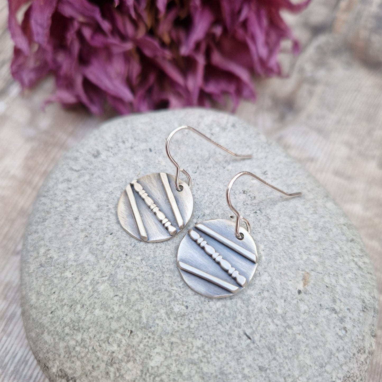 Each earring is an oxidised Sterling Silver disc with one raised straight line, one raised beaded line and one raised straight line at angles to each other across the disc, attached to earring wire.