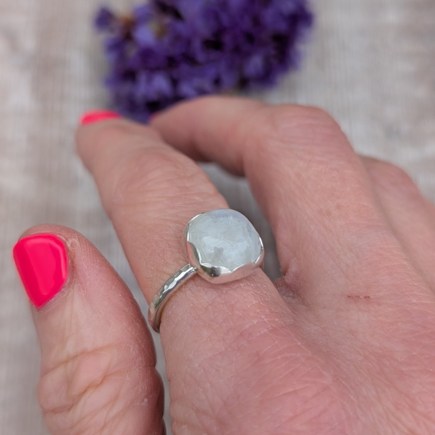 Silver Moonstone Ring worn on a hand, showing the hammered band and soft glowing moonstone stone.