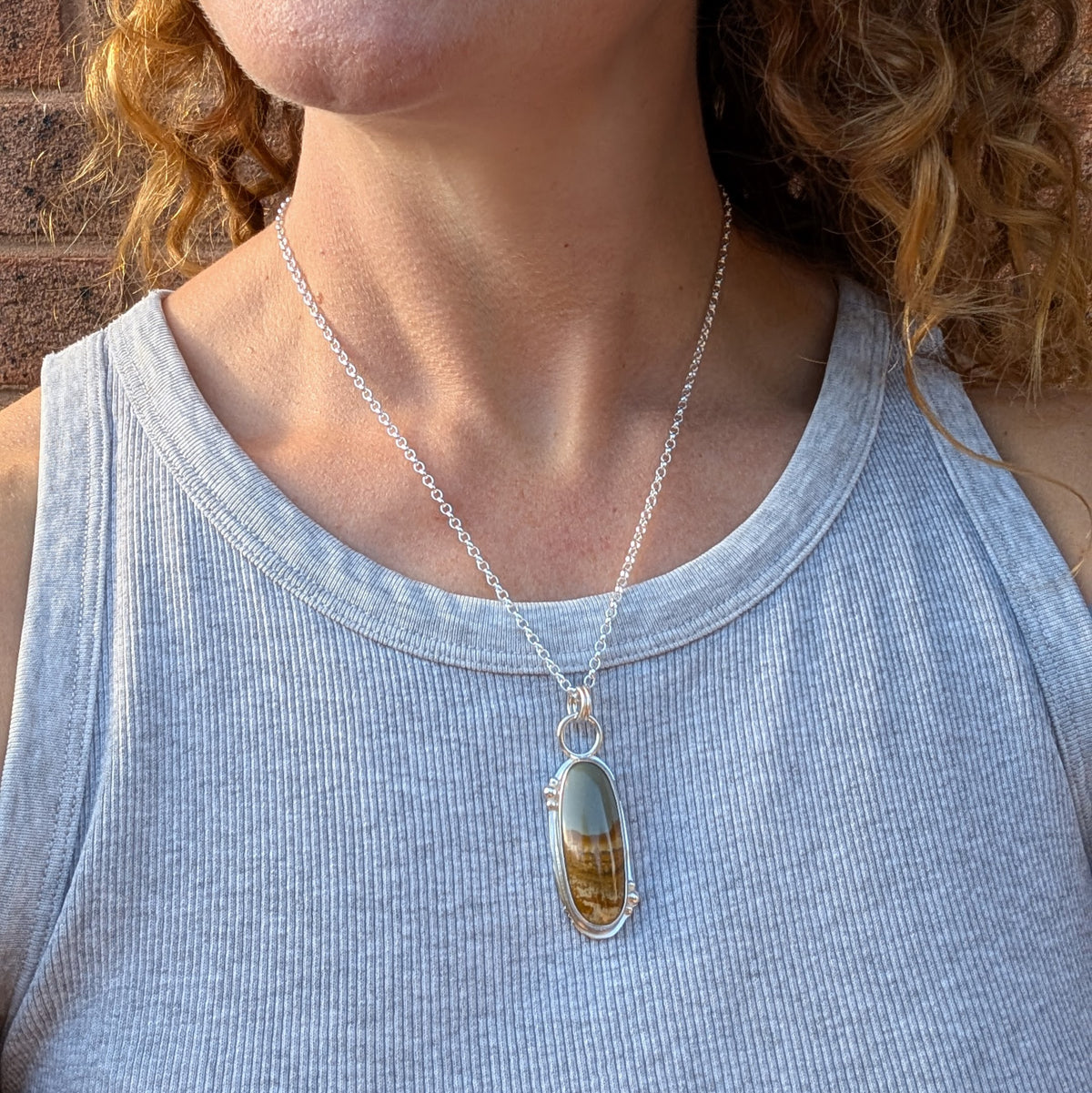 Owyhee Picture Jasper Statement Gemstone Necklace handmade from recycled Sterling Silver, featuring a long oval green and brown gemstone pendant worn on a silver chain.