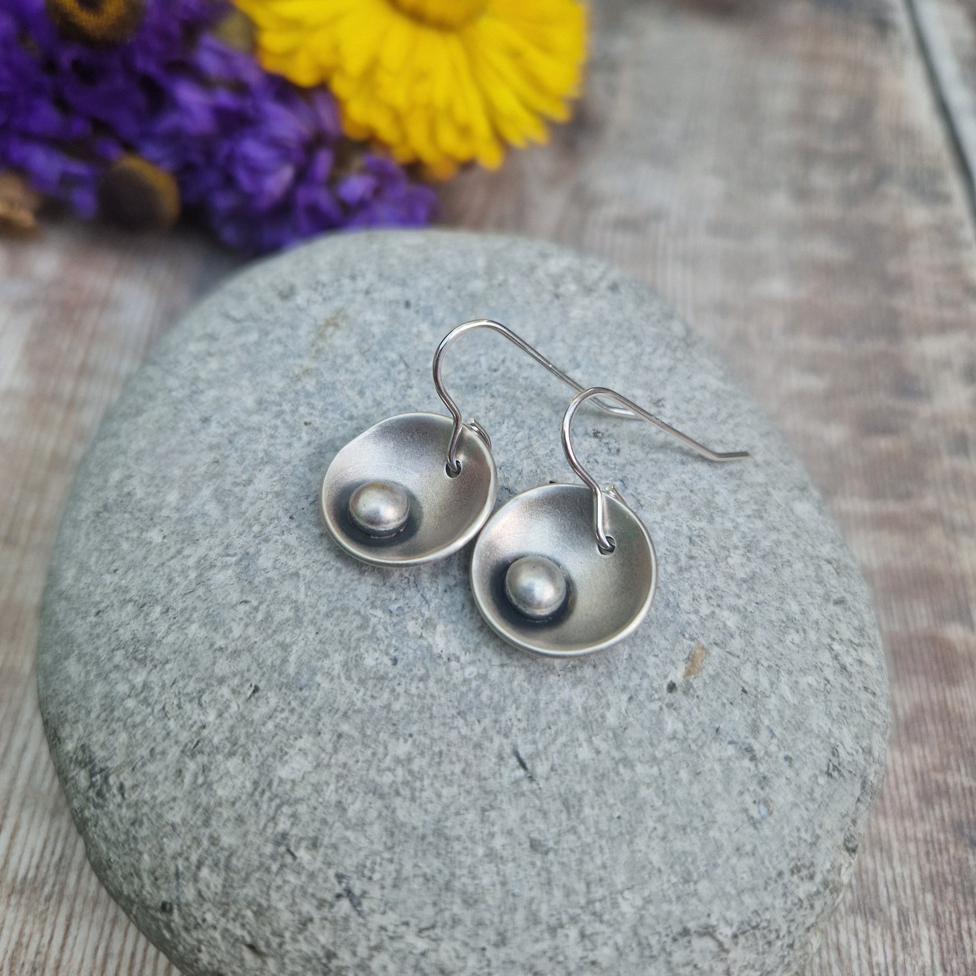 Oxidised Sterling Silver domed disc suspended from silver earring wire with oxidised silver pebble attached to the inside of the dome.