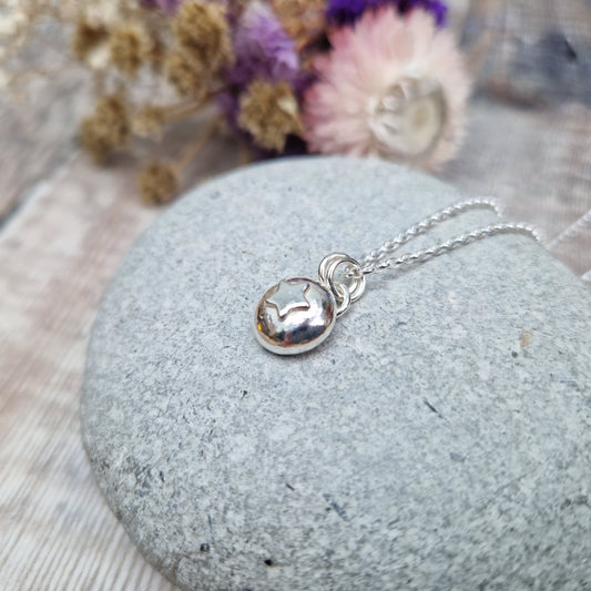 Sterling Silver round pebble shaped pendant with slightly raised silver five-pointed star shape at its centre. Suspended from a silver via two small silver circle links.