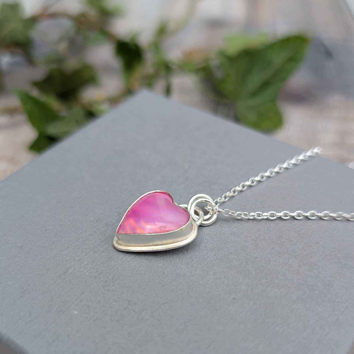 Side-angle close-up of a Pink Aurora Opal Heart Necklace handmade from recycled Sterling Silver, highlighting the depth of the setting and colourful Aurora Opal stone.