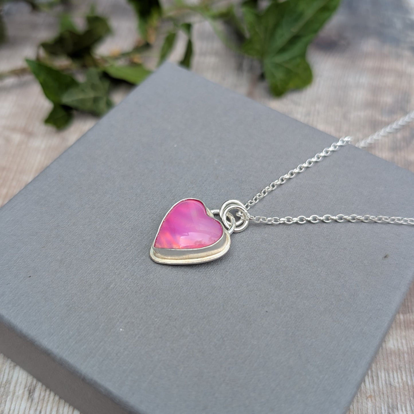 Close-up of a Pink Aurora Opal Heart Necklace handmade from recycled Sterling Silver, showing the pink heart-shaped Aurora Opal in a silver setting.