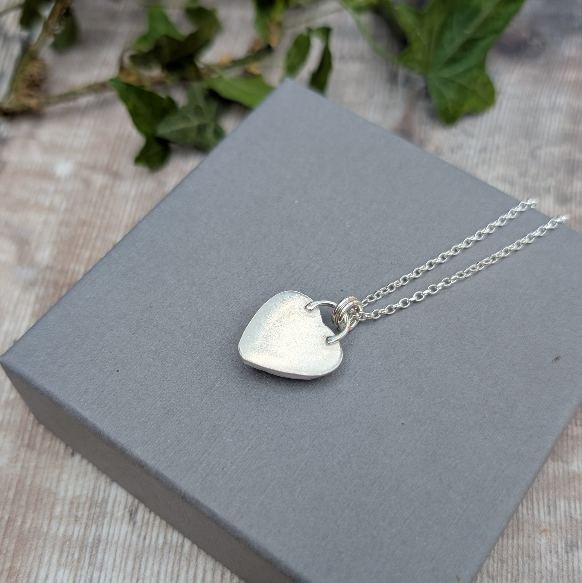 Back view of a Pink Aurora Opal Heart Necklace handmade from recycled Sterling Silver, showing the smooth silver back of the heart pendant.