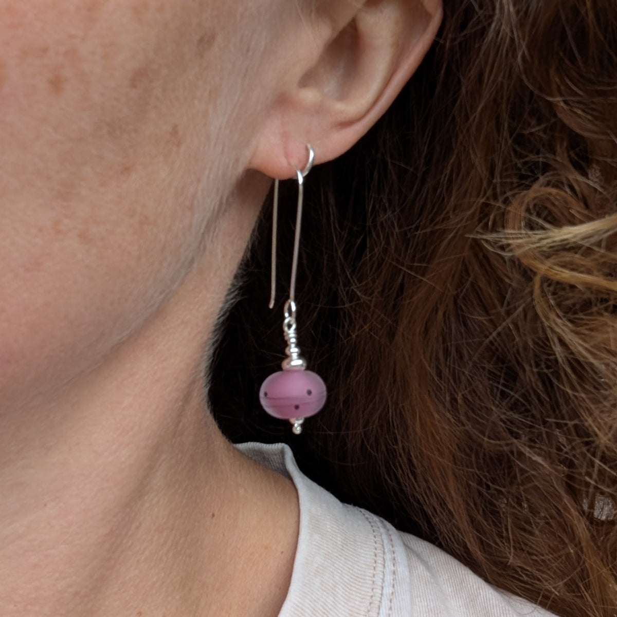 pink scribbles lampwork glass long silver earrings being worn, showing how the long recycled Sterling Silver earrings hang from the ear.