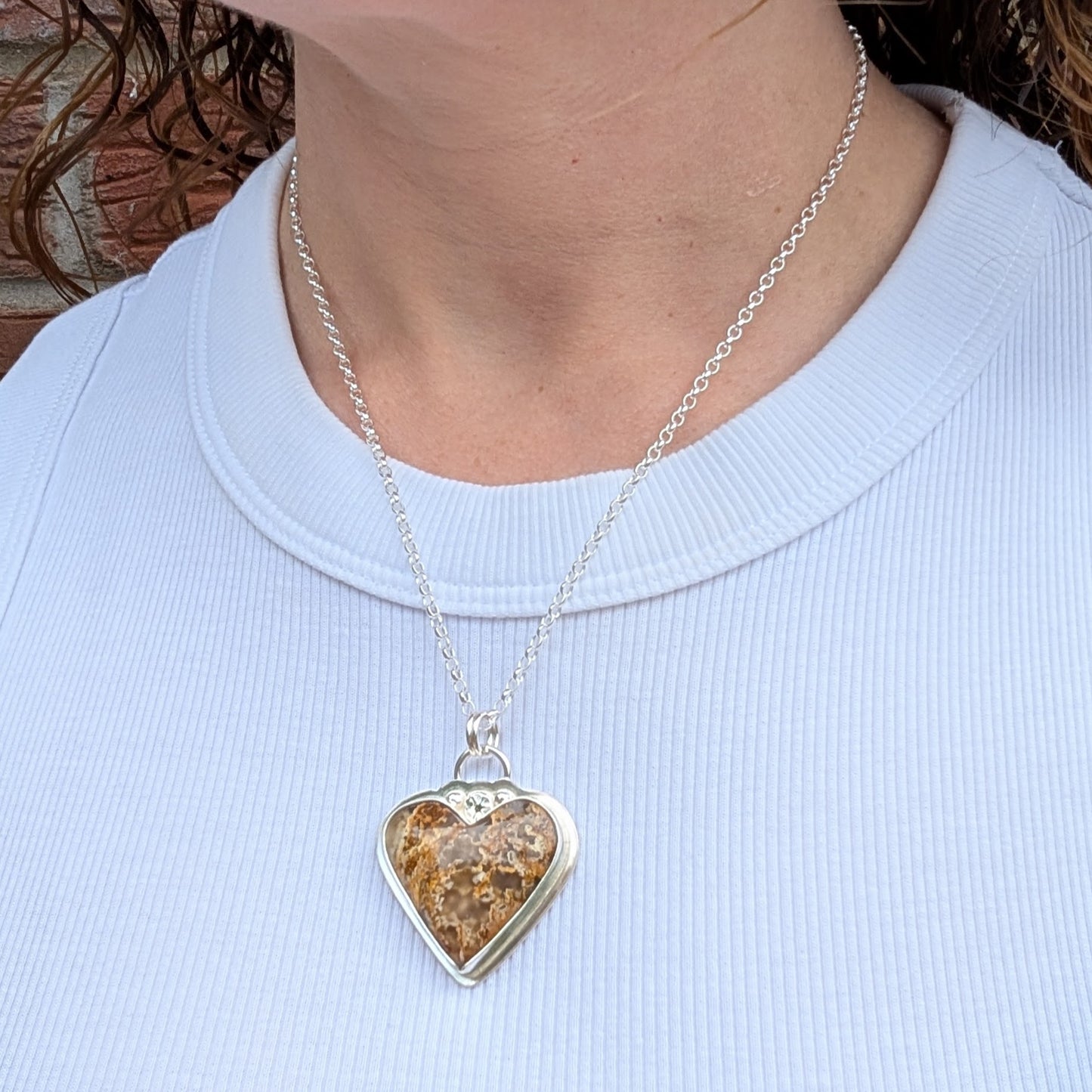 Plume Agate Heart Necklace worn on a chain showing how it sits on the neck
