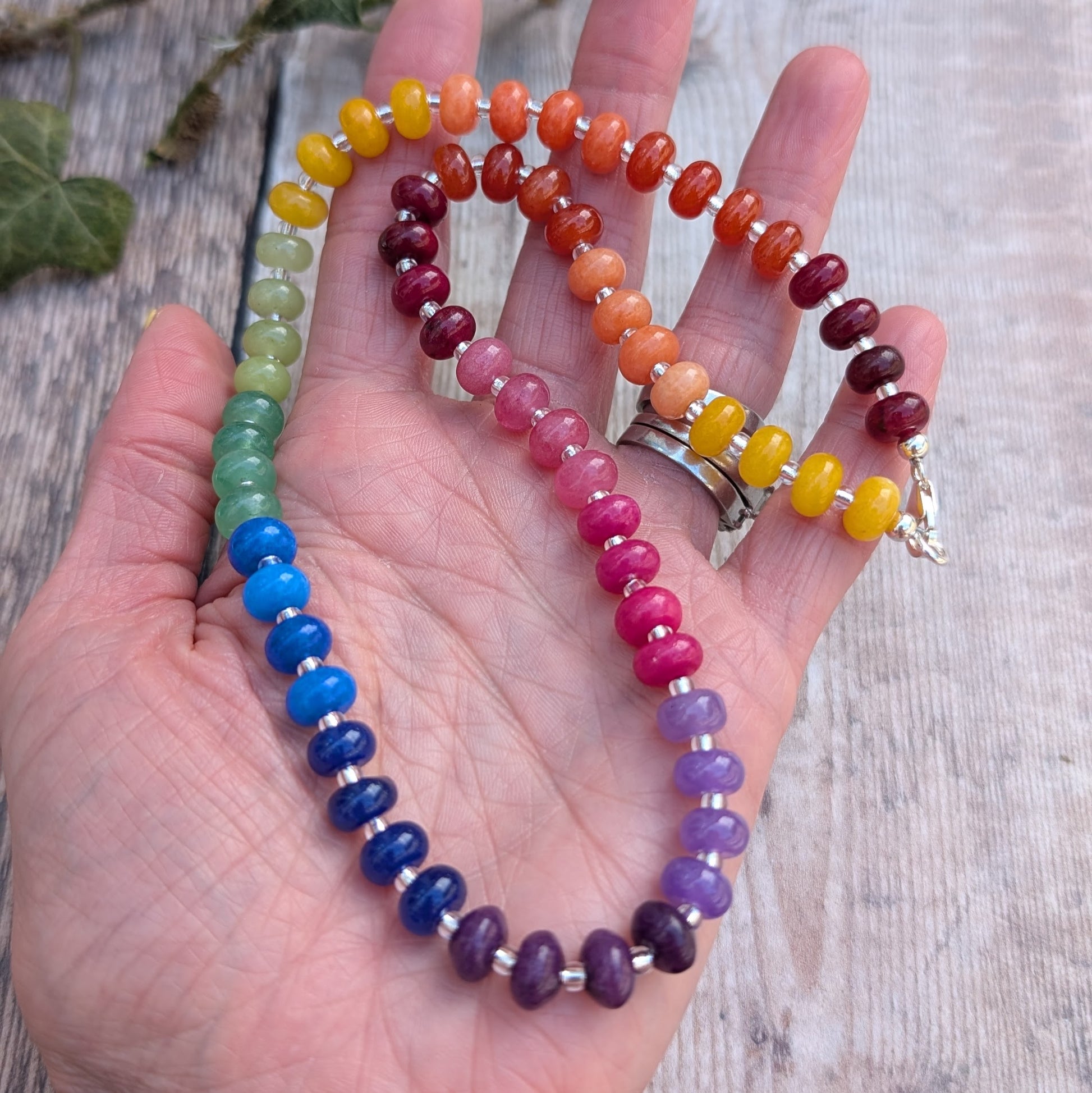 Rainbow Jade Bead Necklace held in a hand, displaying the full range of colourful jade beads and recycled Sterling Silver spacers and clasp.