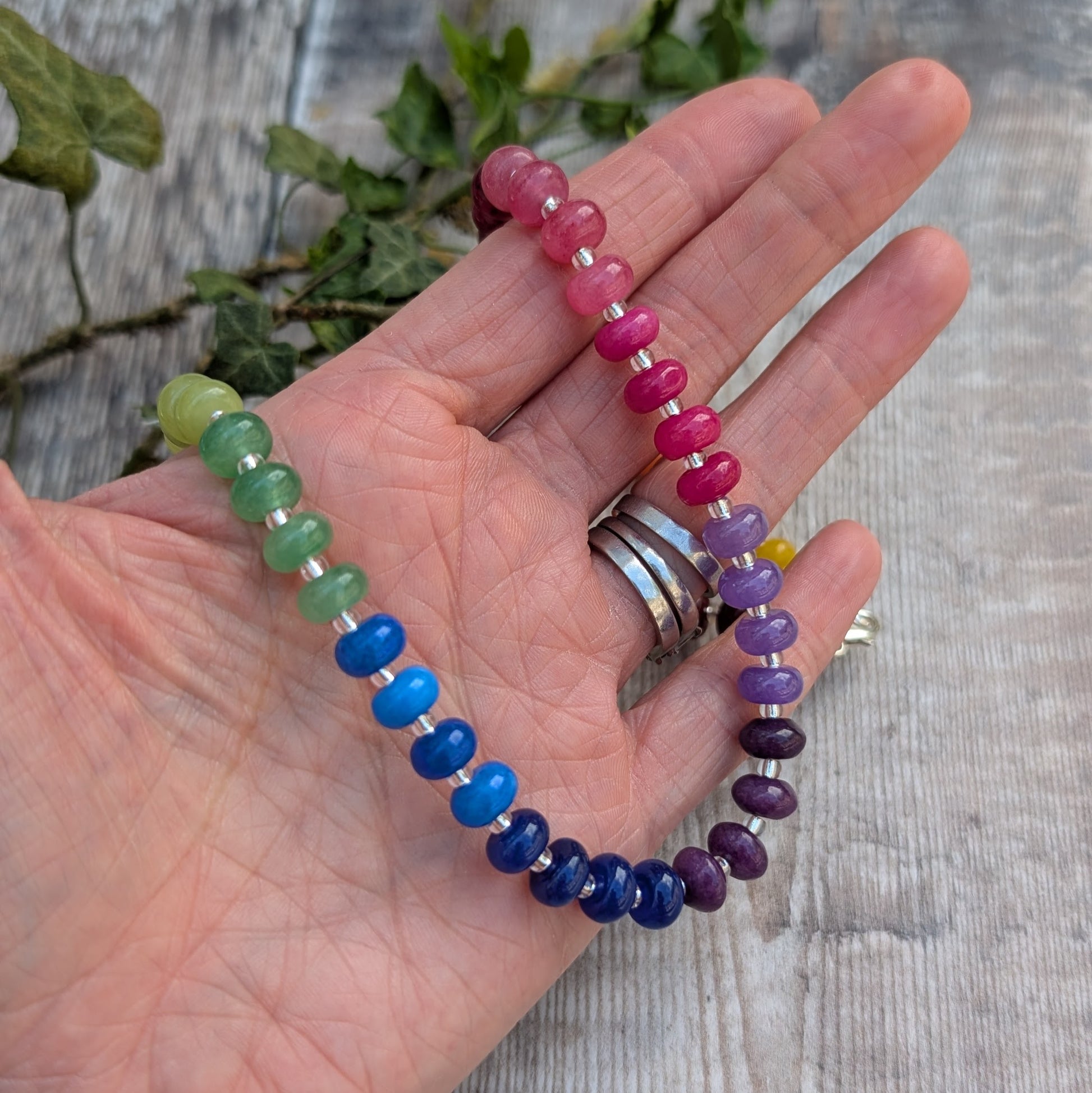 Rainbow Jade Bead Necklace held in a hand, showing colourful jade beads in shades of pink, purple, blue and green with recycled Sterling Silver spacers.