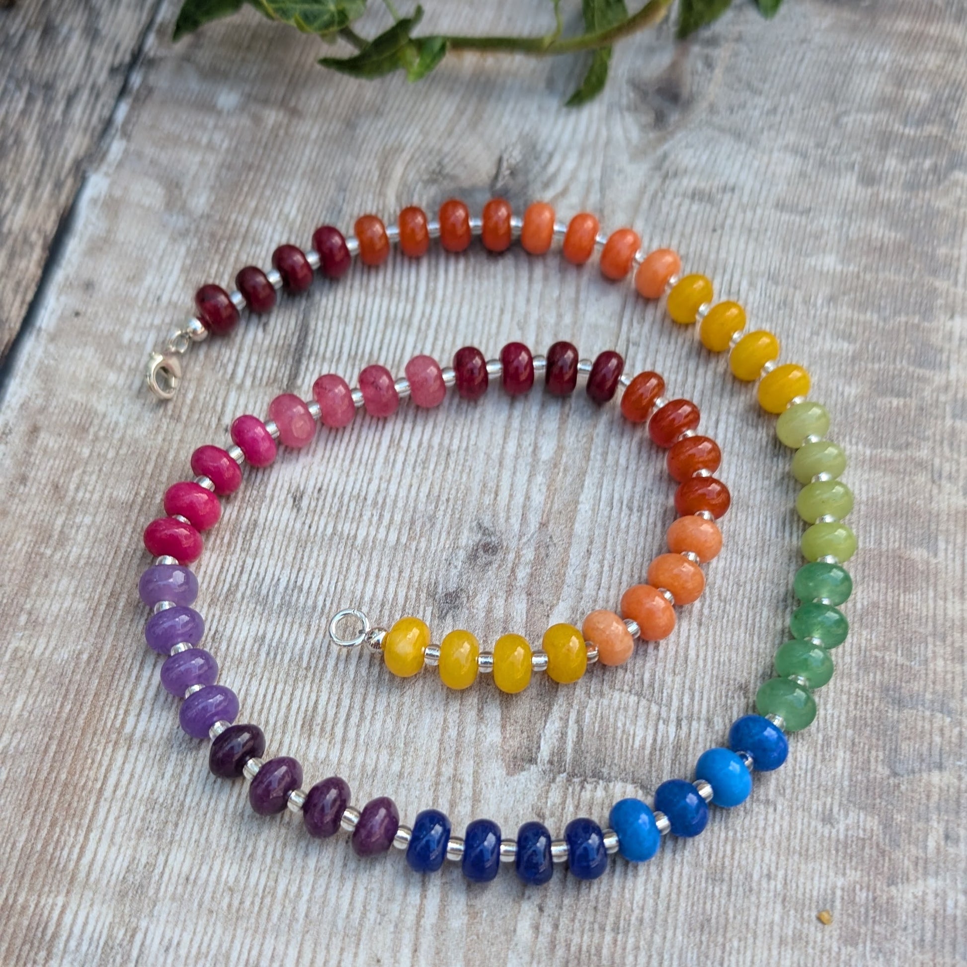 Rainbow Jade Bead Necklace laid out on a wooden surface, showing the full strand of colourful jade beads and Sterling Silver clasp.