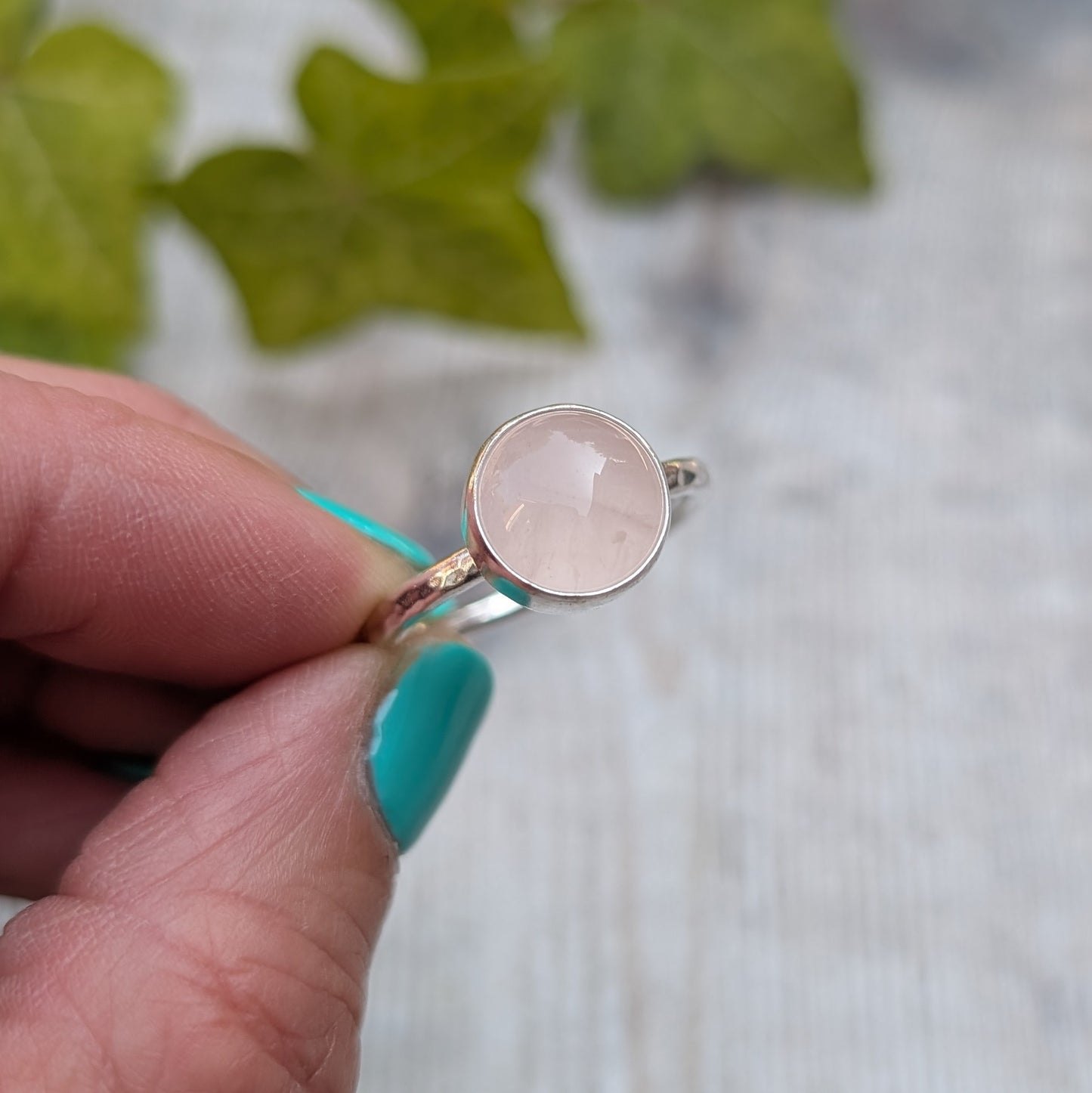 Close up of a rose quartz ring size R handmade from recycled Sterling Silver, featuring a round pale pink rose quartz gemstone in a simple bezel setting.