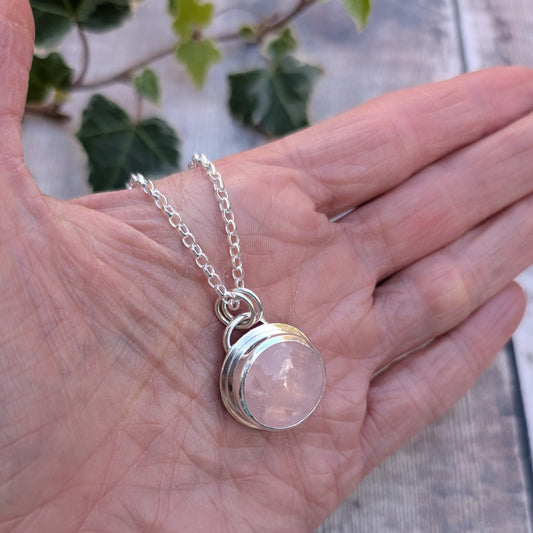 Rose Quartz Statement Gemstone Necklace handmade from recycled sterling silver, featuring a round pale pink gemstone in a polished silver setting, resting in the palm of a hand.