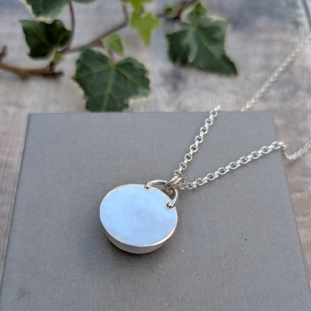 Back view of the Rose Quartz Statement Gemstone Necklace showing the smooth sterling silver backing and handmade silver loops connecting the pendant to the chain.
