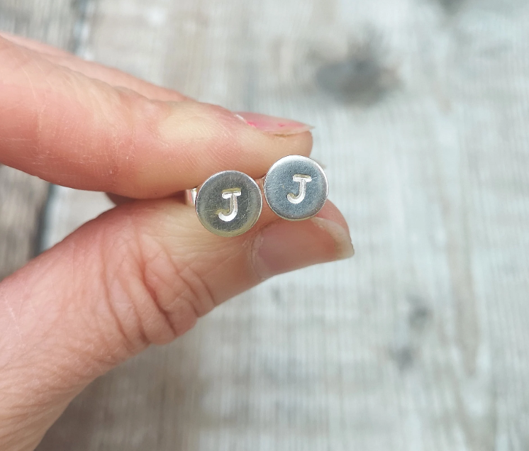 Each earring is a small Sterling Silver disc with an initial stamped in the centre. Mounted onto a silver stud wire.