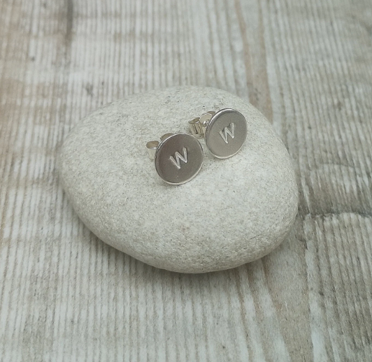 Each earring is a small Sterling Silver disc with an initial stamped in the centre. Mounted onto a silver stud wire.