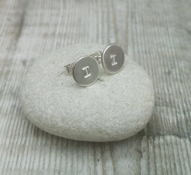 Each earring is a small Sterling Silver disc with an initial stamped in the centre. Mounted onto a silver stud wire.