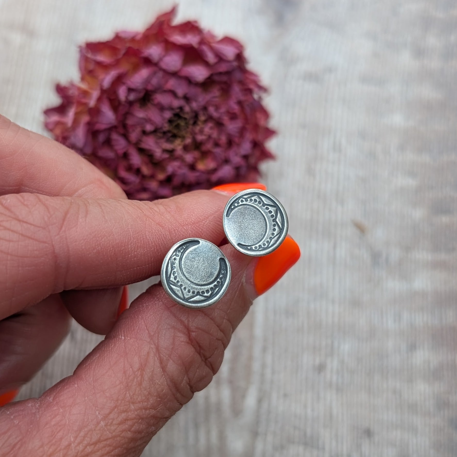 Close-up of oxidised silver moon disc earrings with detailed crescent moon pattern.