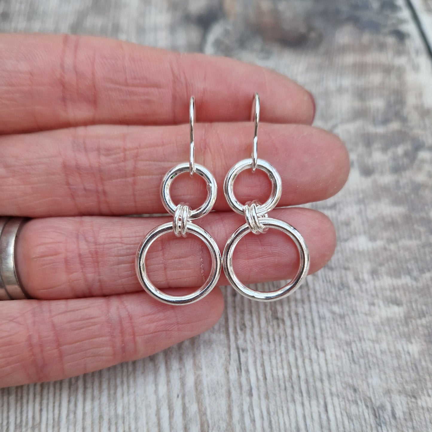 Stirling Silver two circle drop earrings. Each earring has one smaller silver open circle attached to silver earring wire. Attached to the small open circle via two small hoops is a larger open silver circle measuring 15mm in diameter. Approximately 35mm drop including earring hook providing lots of movement.