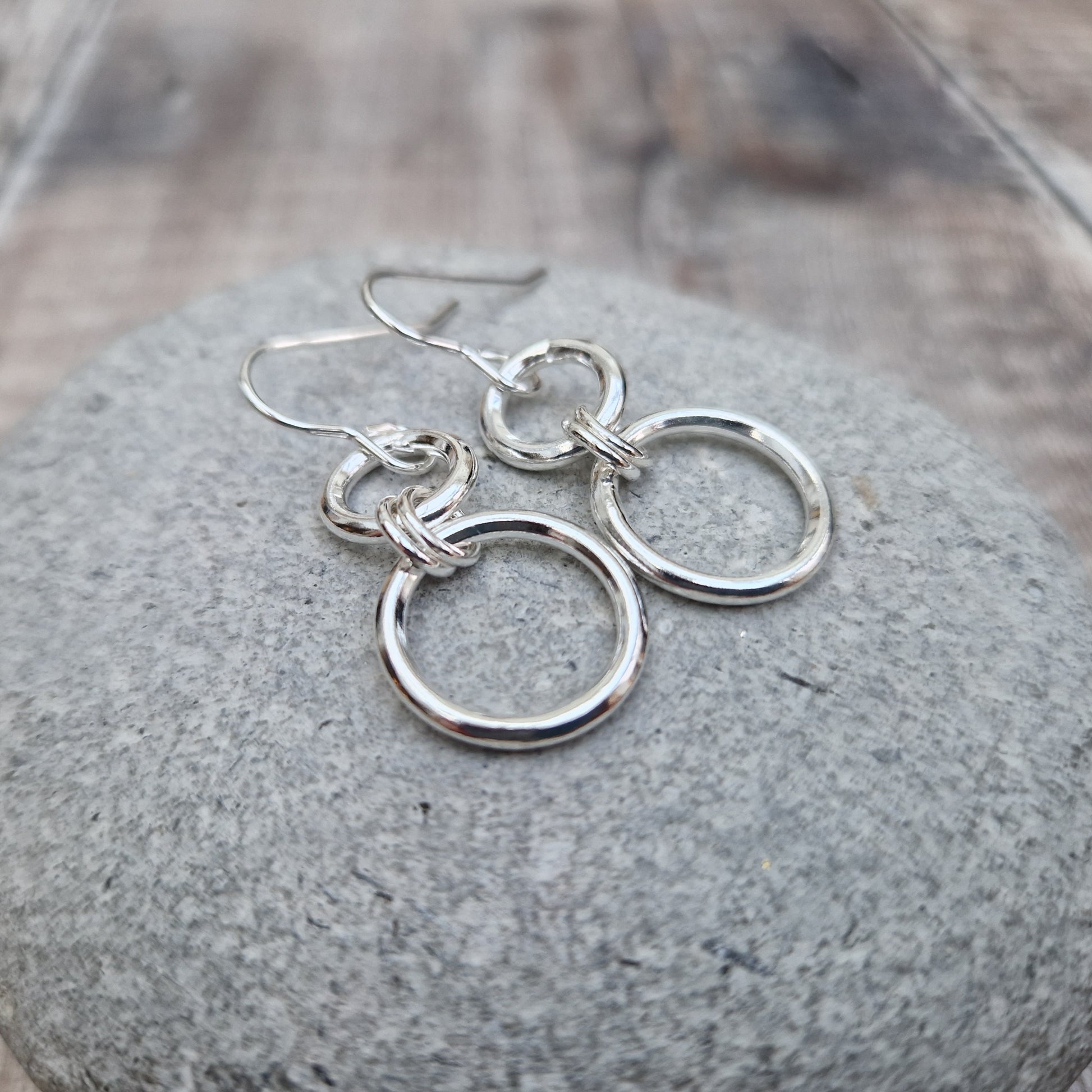 Stirling Silver two circle drop earrings. Each earring has one smaller silver open circle attached to silver earring wire. Attached to the small open circle via two small hoops is a larger open silver circle measuring 15mm in diameter. Approximately 35mm drop including earring hook providing lots of movement.