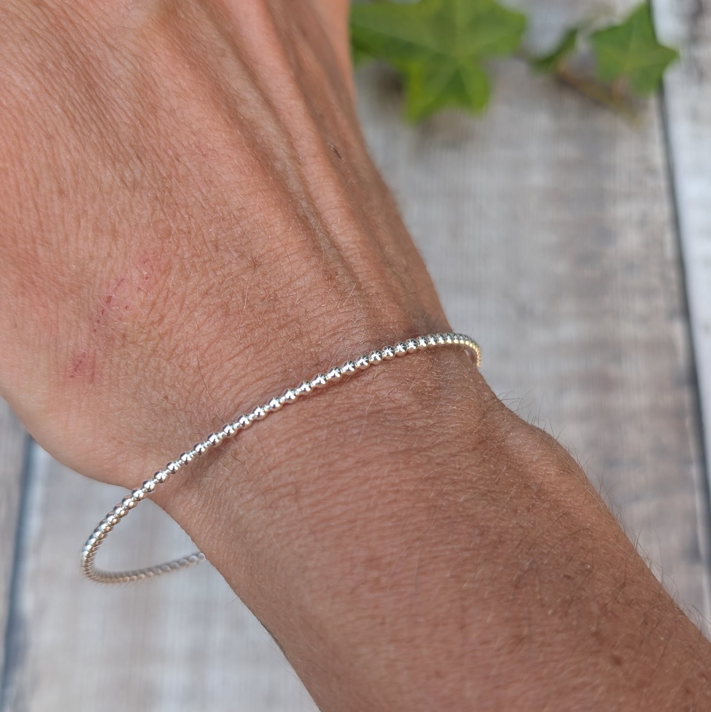 Silver 2mm Beaded Round Bangle worn on the wrist, showing the simple round shape and beaded silver texture.