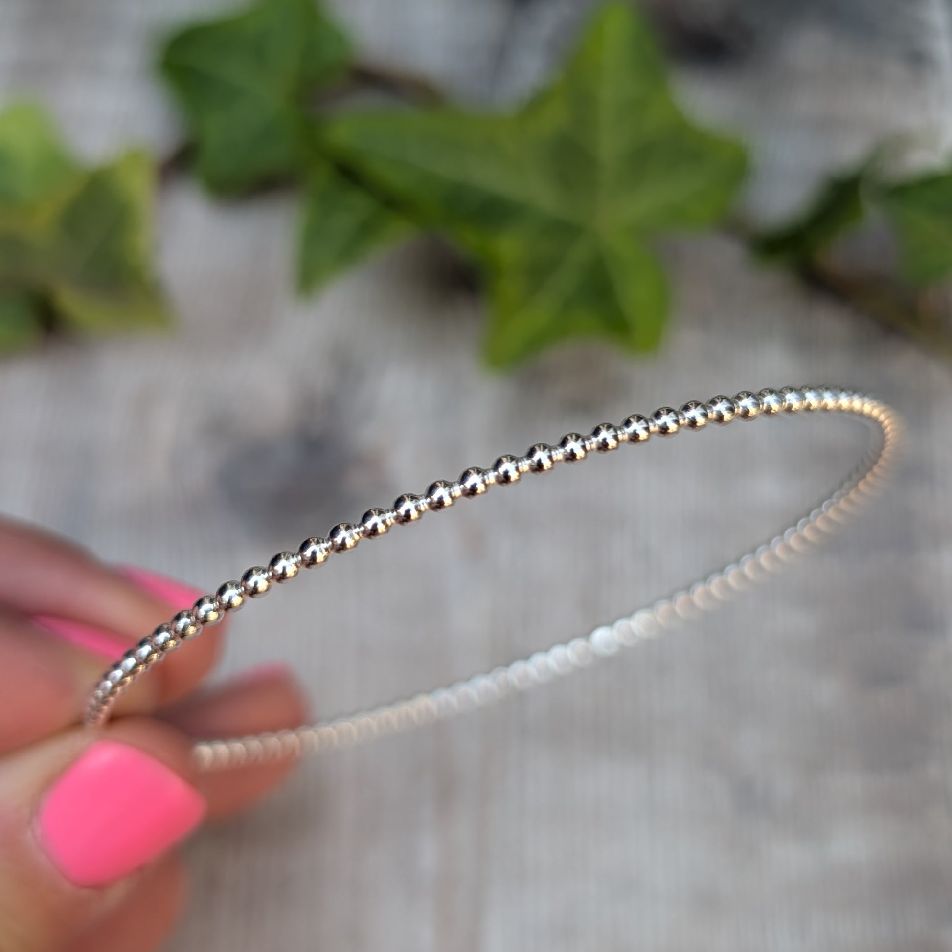 Close up of a Silver 2mm Beaded Round Bangle held in the hand, showing the detailed beaded Sterling Silver wire.