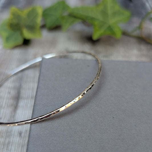 Detailed close up of a Silver 2mm Hammered Round Bangle showing the textured recycled Sterling Silver catching the light.